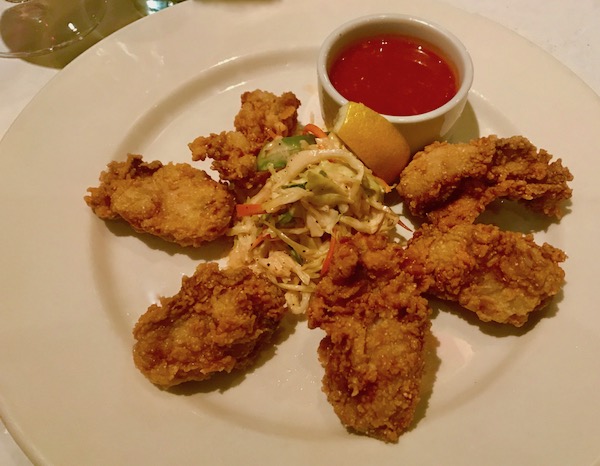 Cornmeal Fried Oysters surrounding coleslaw and sauce on a white plate