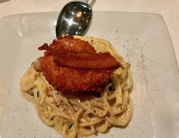 Housemade Spaghetti with Guanciale and Fried-Poached Farm Egg on a white plate