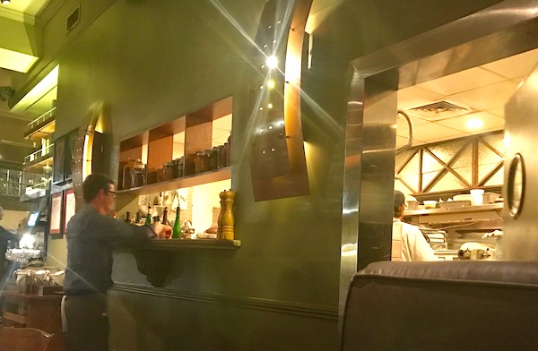 A waiter at an open kitchen in a restaurant