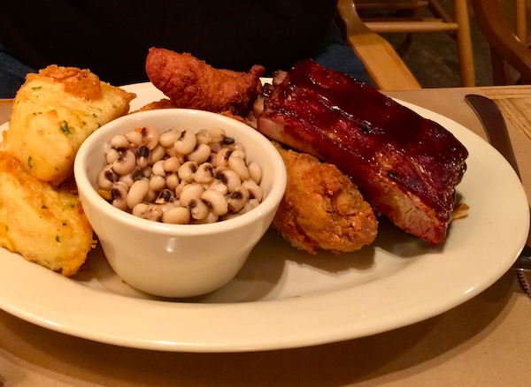 Fried Chicken and Ribs Combo on a white plate with a dish of black eyed peas and corn bread