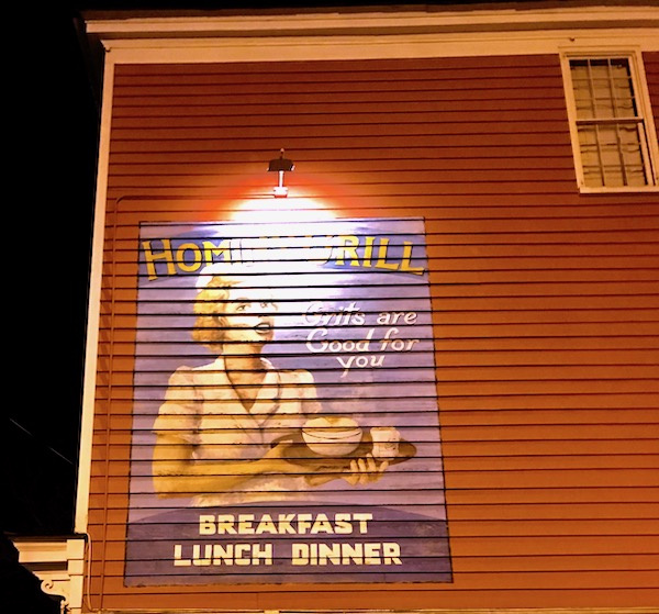 The outside of a building with shingles and a painted mural of a waitress