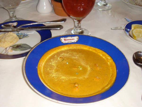 A cobalt blue rimmed soup bowl filled with Bisque of Curried Pumpkin Crawfish and Corn. 