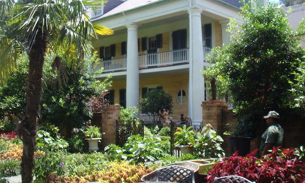 A large plantation style pale yellow home with gardens
