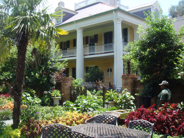A large plantation style pale yellow home with gardens