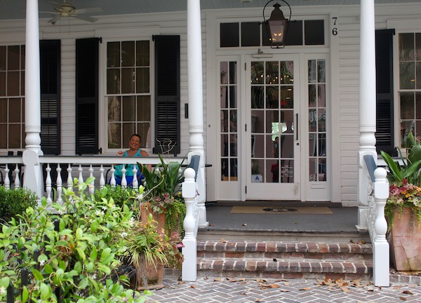A woman waving from a chair on a southern style porch.