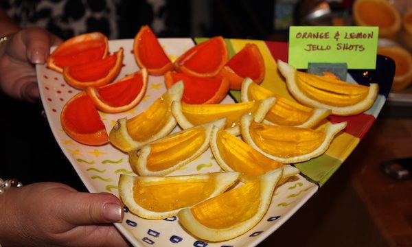 A triangular painted ceramic plate with lemon rind jello shot wedges and orange rind jello shot wedges.