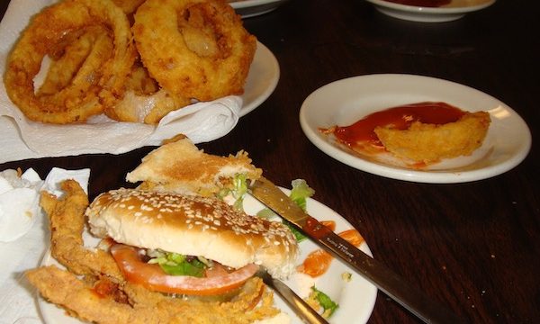 A dark wood topped table with three plates of food.