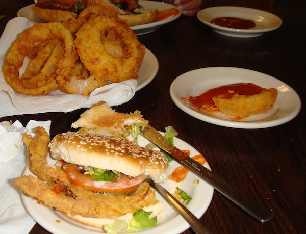 A dark wood topped table with three plates of food.