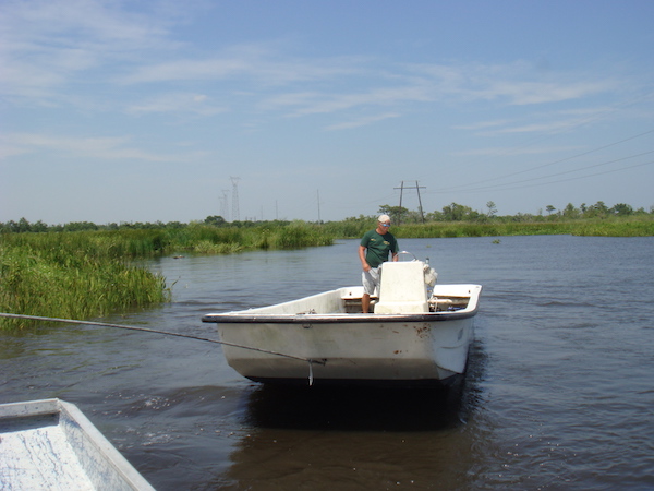 A man in a small boat towing another boat.