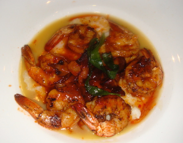 A white soup plate filled with grits and shrimp