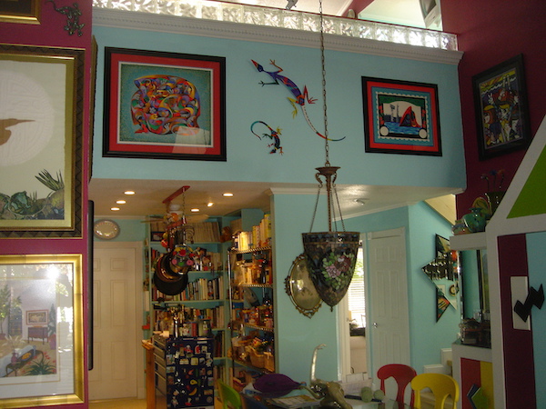 An aqua wall with artwork and two colorful metal lizards