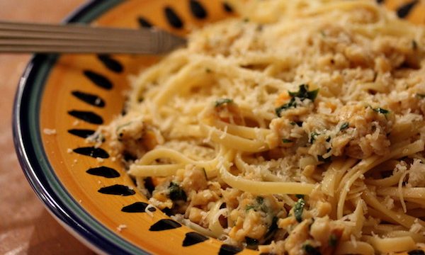 A yellow and blue rimmed pasta bowl filled with Linguine with White Clam Sauce and topped with grated cheese