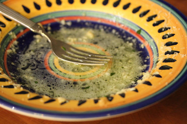A yellow and blue pasta bowl with the remains of sauce and a fork.