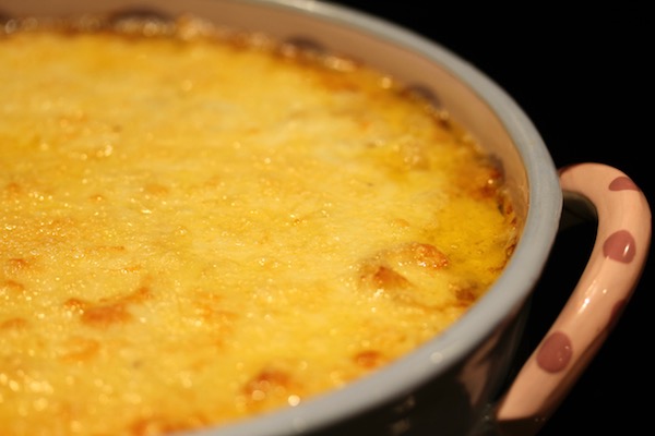 Blue ceramic casserole filled with macaroni and topped with melted cheese with golden brown spots.