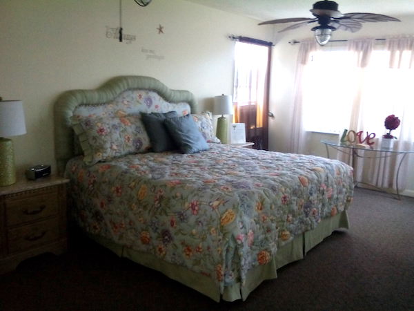 a bedroom with bed covered in floral bedspread and throw pillows