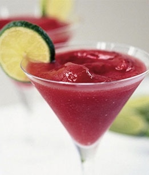 A martini glass filled with cranberry margarita with lime slice on rim of glass.