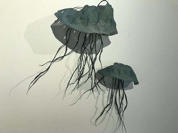 Two metal jelly fish sculptures on a white wall