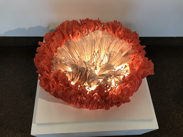 An orange and white glass flower on a pedestal