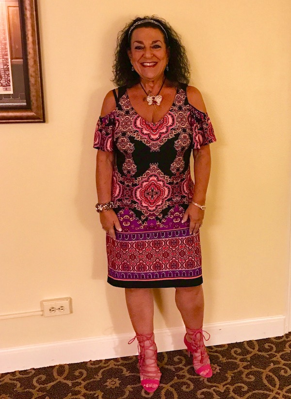 A woman in a pink paisley dress with pink lace up stilettos