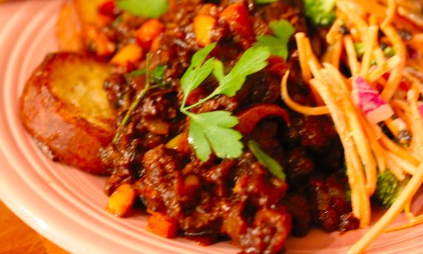 A pink dinner plate piled high with garlic toast, sloppy joe mix and carrot and broccoli salad garnished with parsley sprigs