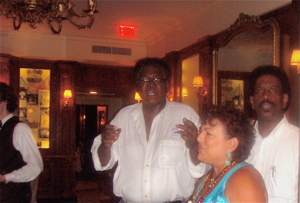 Black man in white shirt and white woman with dark hair in turquoise top singing