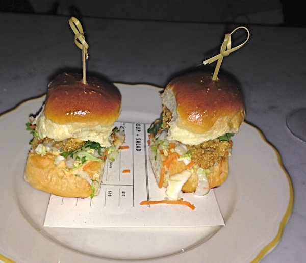 A small white plate with two small rolls filled with fried oysters
