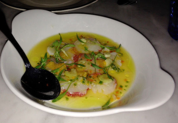A white soup bowl with ears filled with a yellow sauce and chunks of lobster