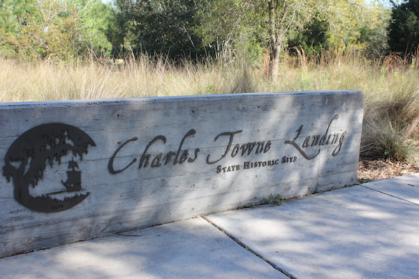 A concrete wall that has black letters that read Charles Towne Landing