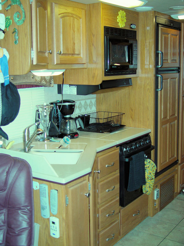 RV kitchen area showing light oak cabinets and white countertop