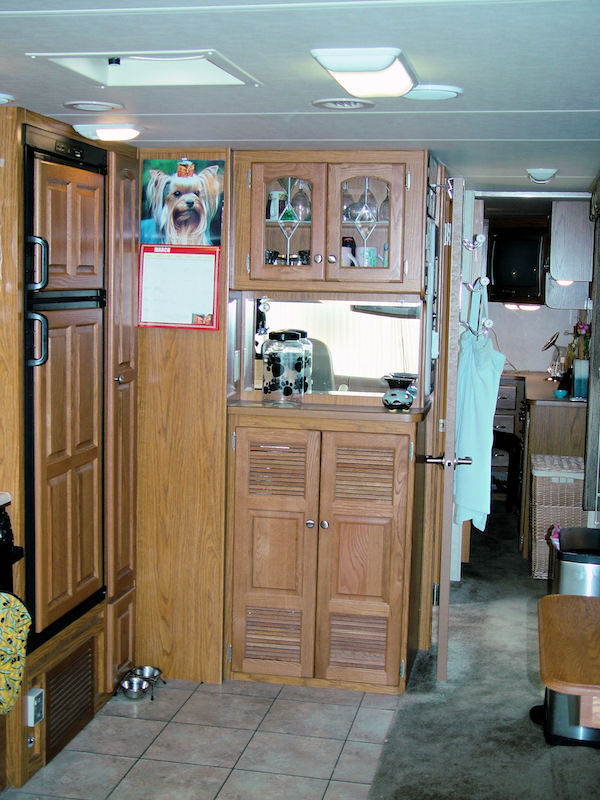 RV kitchen with small fridge and pantry cabinet in light oak