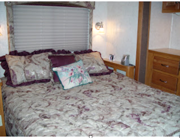 RV bed with mauve, gray and white bed spread and pillows
