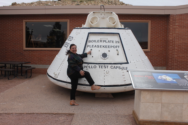An actual space capsule with a woman pretending to enter.