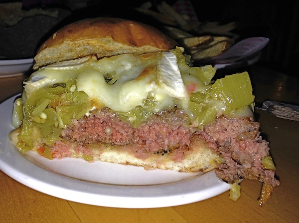 A white plate with Half of “The Mother of Green Chile Cheeseburgers”