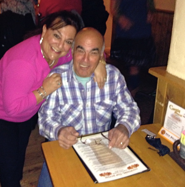 A woman standing and hugging a man who is seated at a BBQ restaurant