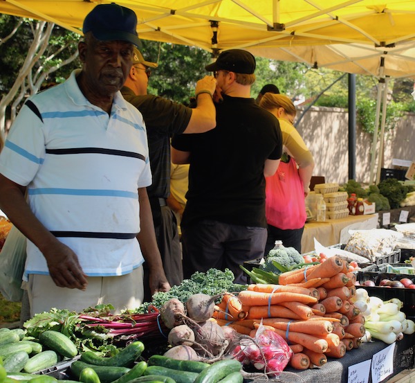 A male produce vendor showing off his veggies