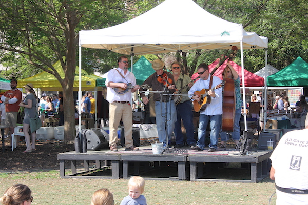 A group of musician playing under a small tent on a platform