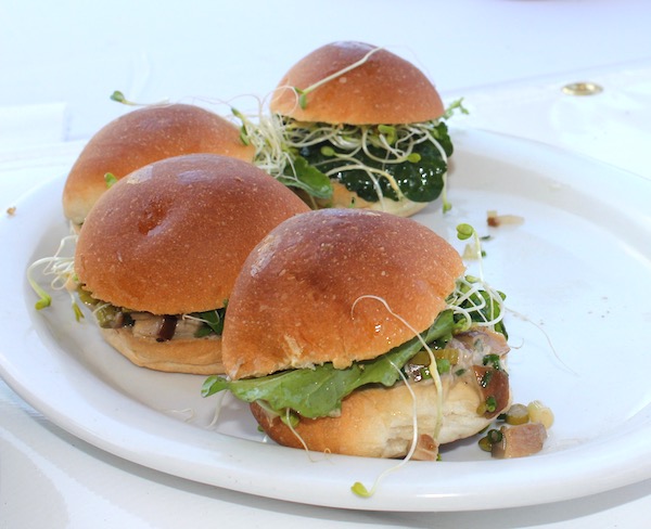 White plate with 4 small rolls filled with mini burgers, mushrooms and lettuce