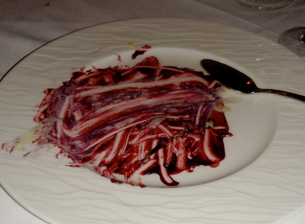 A white plate with the remains of blackberry sauce scraped clean