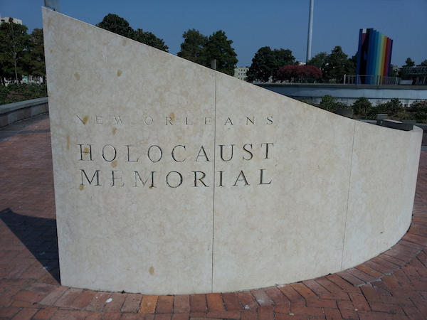 A stone wall with the words New Orleans Holocaust Memorial carved in it.