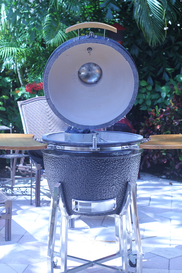 A ceramic grill on a patio with the lid open