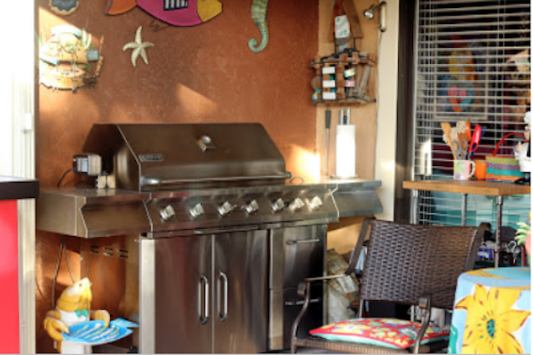 A huge stainless steel gas grill in front of a brown wall