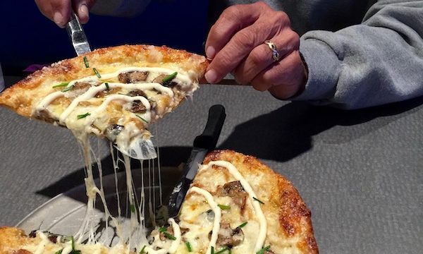 A man cutting a slice from a whole pizza