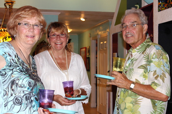 Two women and one man holding small aqua plates with food and plastic glasses filled with sangria.