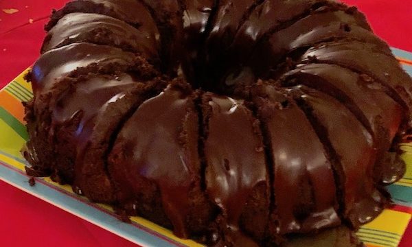 A frosted chocolate bundt cake on a striped plate