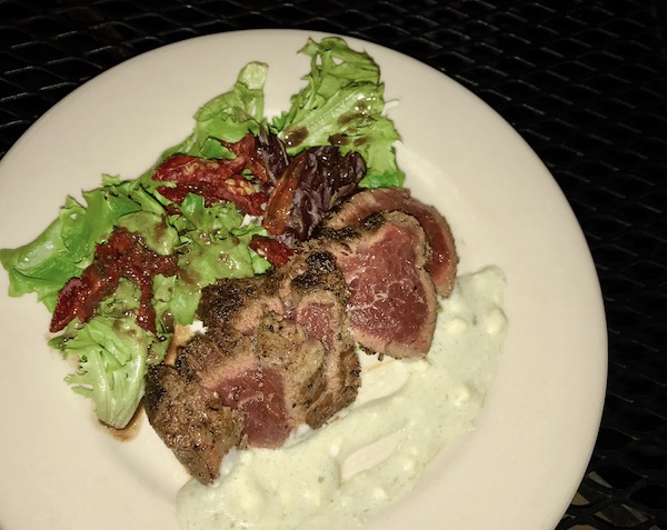Slices of Blackened Beef Tenderloin with Gorgonzola on a white plate with salad