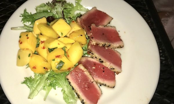 Seared Ahi Tuna and Lemon Ginger Gastrique with Spicy Mango Salad on a white plate