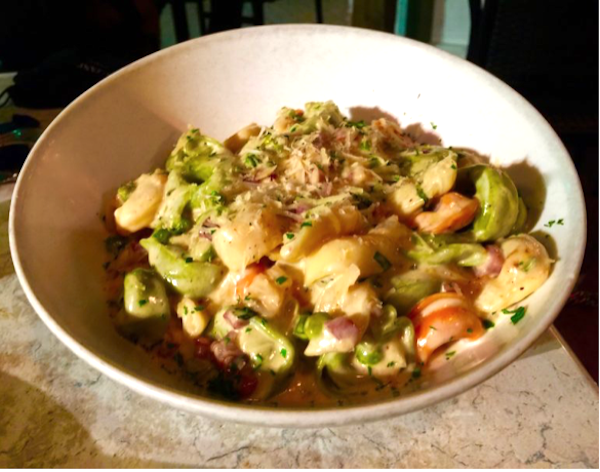 Tricolor tortellini with ham and peas in a white bowl