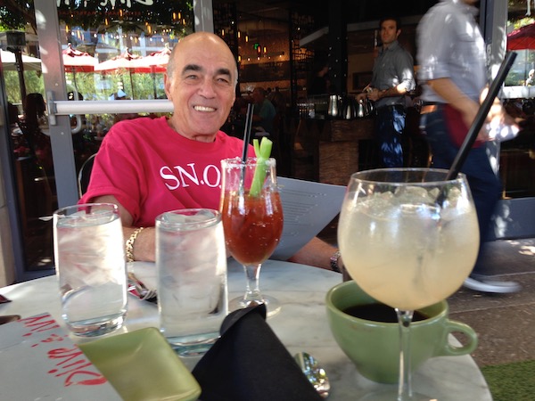 A man in a red t-shirt looking happy in a restaurant.