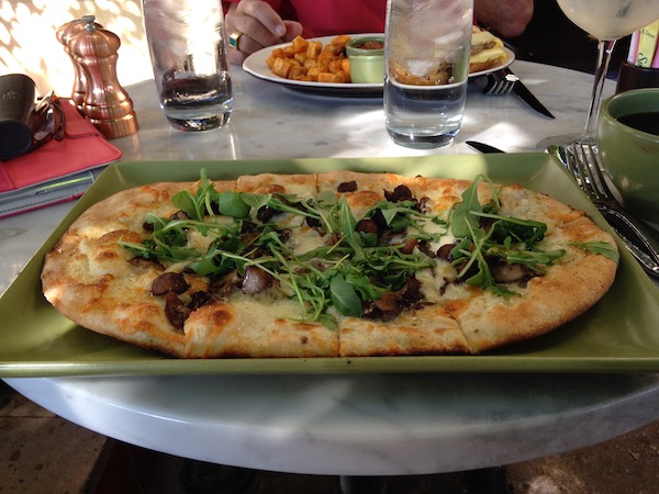 A flat bread pizza on an olive square plate .