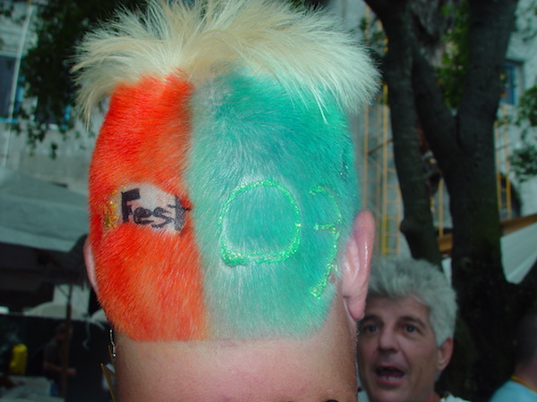 The back of a man's head with hair buzzed and colored orange on left and green on right and SunFest '09 on his hair